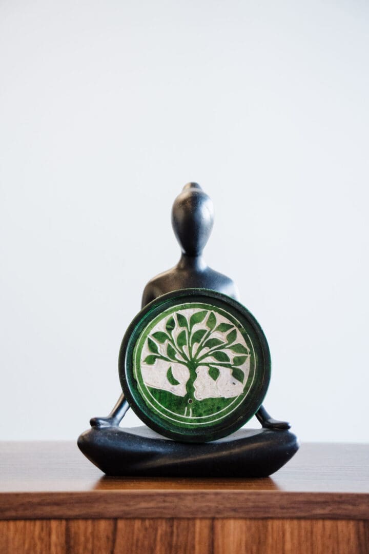 Meditating statue holding green tree of life